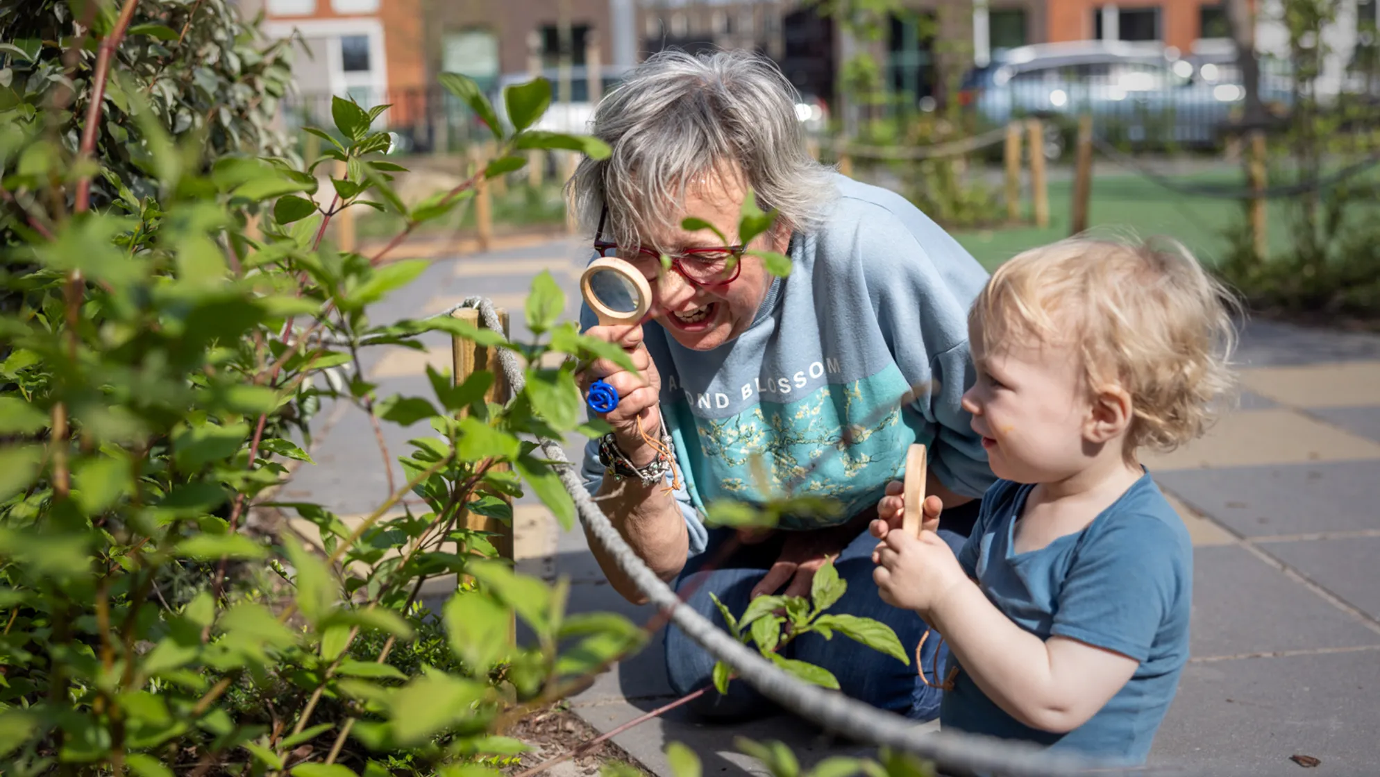 Pedagogisch medewerker en kind kijken samen door een loep naar blaadjes bij kinderopvang Kind&co ludens