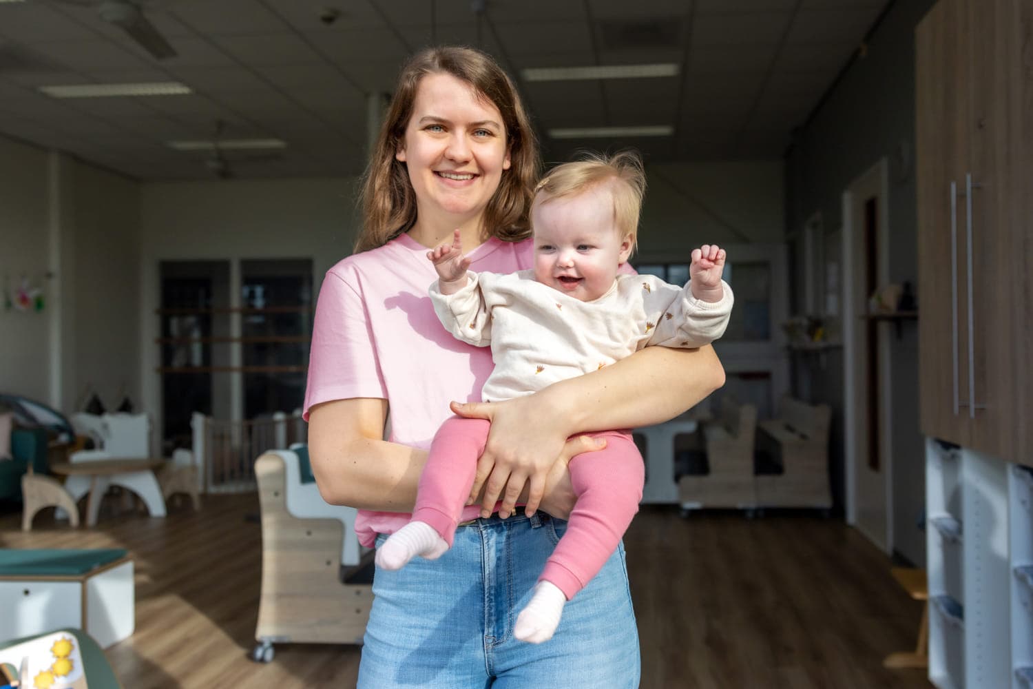 Blij kind op de armen bij een pedagogisch medewerker bij kinderopvang Kind&co ludens