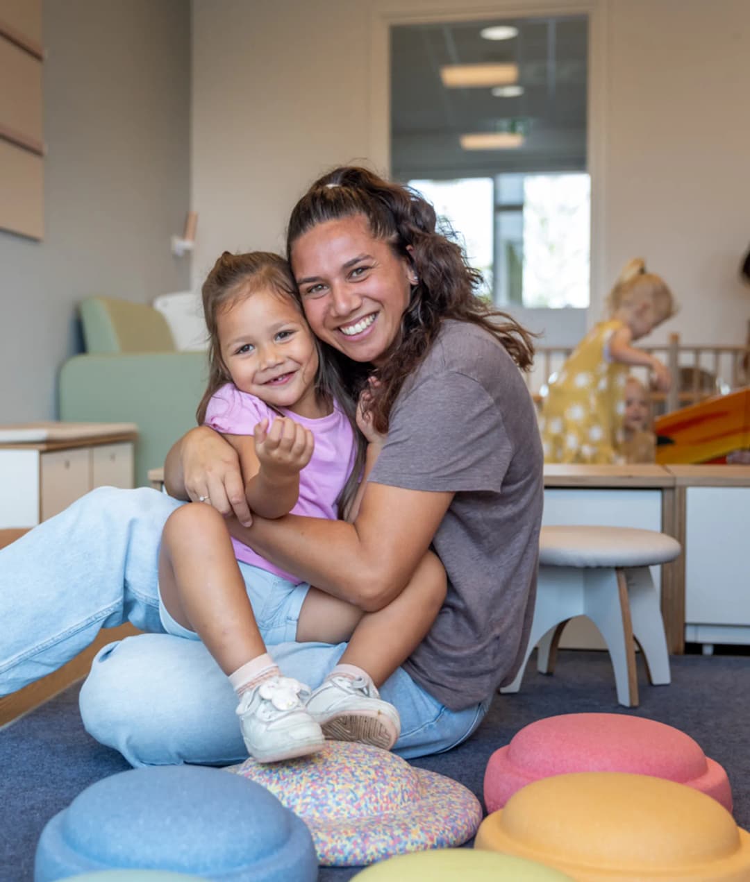 Kind en pedagogisch medewerker knuffelen bij kinderopvang Kind&co ludens